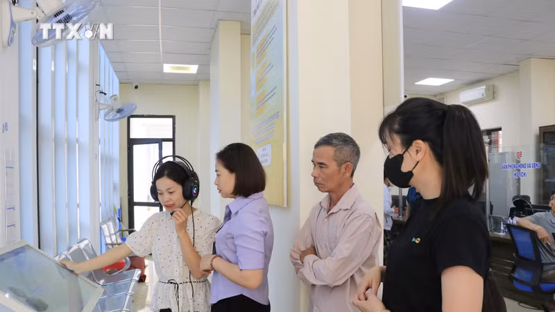 茂阿乡公共行政服务中心干部指导群众在AI Kiosk上进行操作。图片来源：越通社