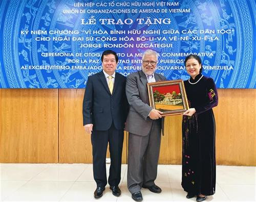 越南友好组织联合会主席阮芳俄(右)向委内瑞拉驻越大使乌斯卡特吉赠送礼物。图自越通社 越南友好组织联合会主席阮芳俄(右)向委内瑞拉驻越大使乌斯卡特吉赠送礼物。图自越通社
