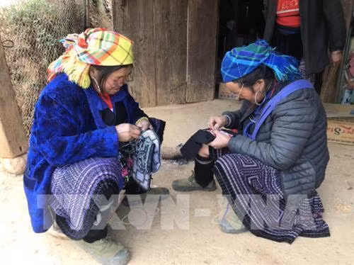 赫蒙族妇女利用空闲时间制作土锦产品。图自越通社