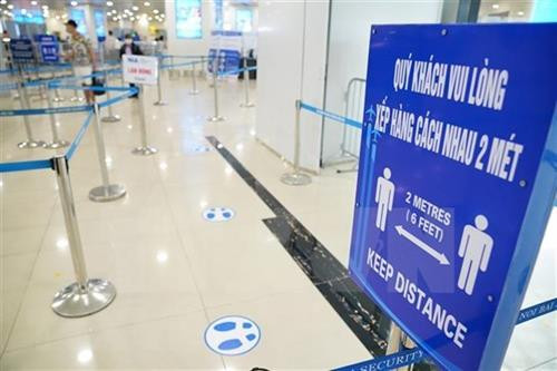 内排国际机场里摆放着提示牌，提醒乘客们保持2米的距离。图自越通社