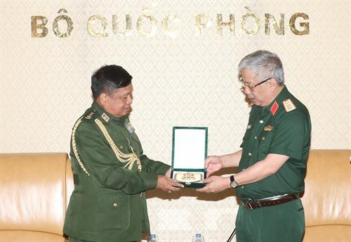 越南国防部副部长阮志咏上将向缅甸军事、海军、空军武官Aung Kyaw Oo大校赠送纪念品。（图片来源：越通社）
