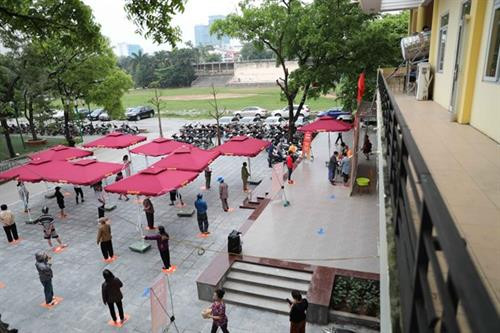 前来领取大米的民众必须佩戴口罩，保持2米的排队距离 。图自越通社