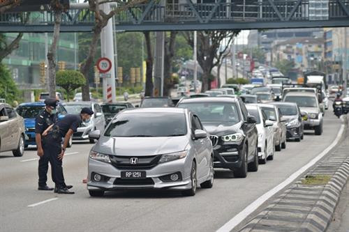 在新冠肺炎疫情蔓延的背景下,马来西亚警方加强对车辆的检查。图自越通社 在新冠肺炎疫情蔓延的背景下,马来西亚警方加强对车辆的检查。图自越通社