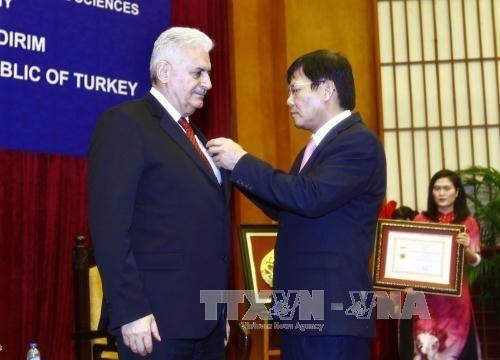 越南社会科学翰林院院长阮光舜教授、博士（右）向比纳利•耶伊尔德勒姆总理授予致力于越南社会科学事业纪念章。（图片来源：越通社）