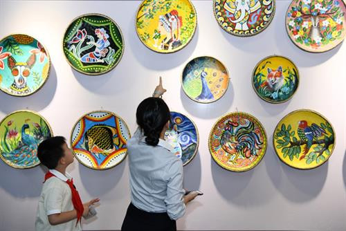 7月22日,师生在中国—东盟少儿艺术教育成果展上参观簸箕画。图自互联网 7月22日,师生在中国—东盟少儿艺术教育成果展上参观簸箕画。图自互联网