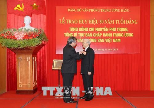 中央书记处常务书记、检查委员会主任陈国旺向越共中央总书记阮富仲授予50年党龄党徽。（图片来源：越通社）