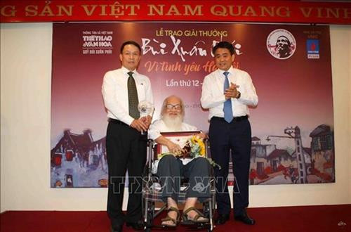 越通社社长阮德利和河内市人民委员会主席阮德钟向 “河内之爱”大奖得奖者阮承喜优秀教育家、副教授颁奖。图自越通社