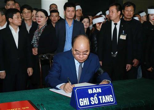 阮春福总理在吊唁簿上题词时。图自越通社