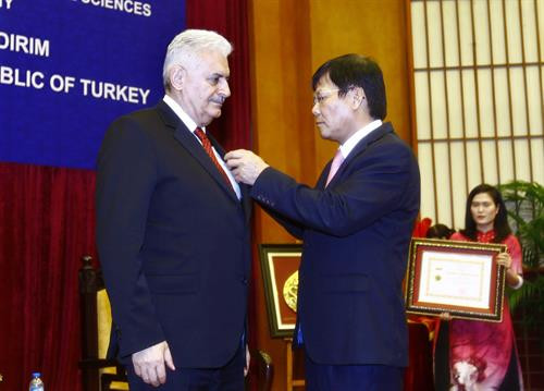 越南社会科学翰林院领导向土耳其总理比纳勒·耶尔德勒姆授予“致力于社会科学事业”纪念章。（图片来源：越通社）