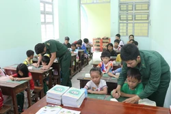 绿衣老师们耐心地引导孩子们书写每一笔每一画。图自越通社