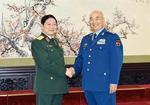 吴春历与许其亮亲切握手 图自越通社