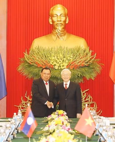 越共中央总书记阮富仲与老挝人民革命党中央委员会总书记、 国家主席本扬亲切握手。（图片来源：越通社）