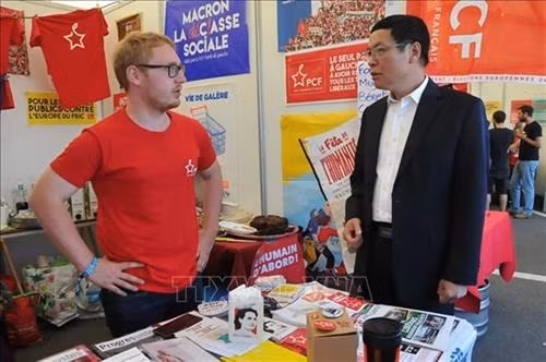 武光英大使参观法国共产党展位。图自越通社