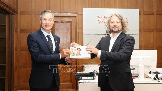 柏林经济部国务秘书克里斯蒂安·瑞克茨代表柏林市政府向越南驻德大使阮明宇象征性地捐赠了上述快速检测试剂盒。图自越通社 德国首都柏林向越南捐赠3万套快速检测试剂盒 ảnh 1
